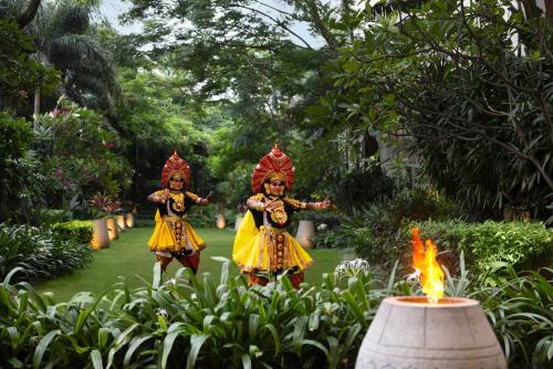 two women in traditional costumes standing in front of a fire at The Ritz-Carlton, Bangalore in Bengaluru
