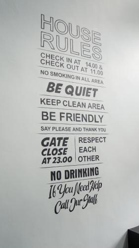 a wall with a house rules wall art at Holabeds Hostel in Solo
