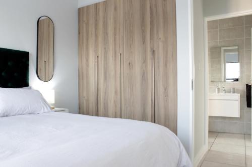 a bedroom with a white bed and a wooden cabinet at The Jade Escape in Cape Town