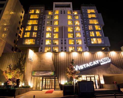 a high rise building with a lit up sign at night at Vistacay Hotel Worldcup in Seogwipo