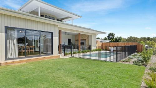 a house with a fence and a yard at Pirama - The Vintage Holiday Houses in Pokolbin