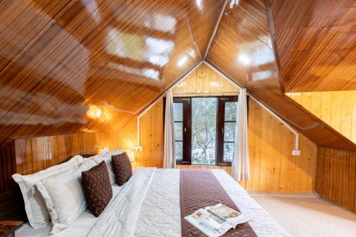 a bedroom with a large bed in a room with wooden walls at Water's Edge by VEO - Part of StayVista in Chak-i-Dāra