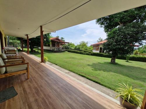 an outdoor deck with a bench and a yard at Villa Alessandra Homestay in Moalboal