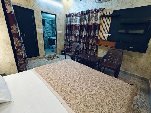 a bedroom with a bed and two chairs and a mirror at Shreeji Inn Homestay in Rishīkesh