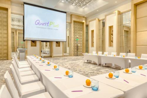 a conference room with white tables and a large screen at Quest Plus Conference Center, Clark in Clark