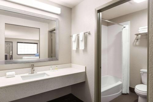 a bathroom with a sink and a toilet and a mirror at Days Inn by Wyndham San Antonio Near Fiesta Park in San Antonio