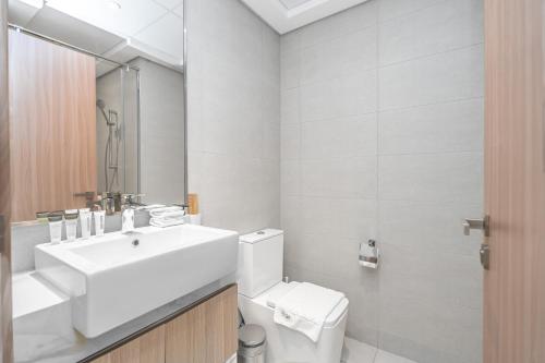 Escape24 Stylish Studio Azizi Riviera 8 Meydan one Dubai في دبي: حمام أبيض مع حوض ومرحاض