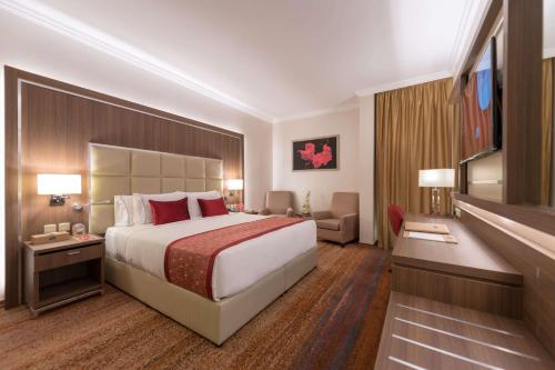 a hotel room with a large bed and a television at Ramada by Wyndham Continental Jeddah in Jeddah