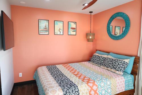 a bedroom with orange walls with a bed and a mirror at Oahu's Best Kept Secret in Laie