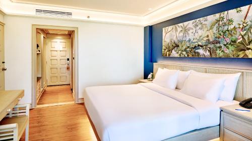 a bedroom with a white bed and a painting on the wall at Beyond Kata in Kata Beach