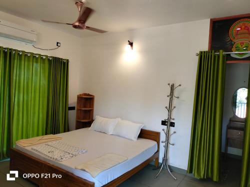 a bedroom with a bed with a green curtain at MARARI SEA SCAPE HOMESTAY Beach in Mararikulam