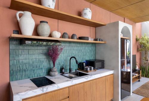 a kitchen with a sink and some vases on the wall at Terra Villas Canggu in Canggu