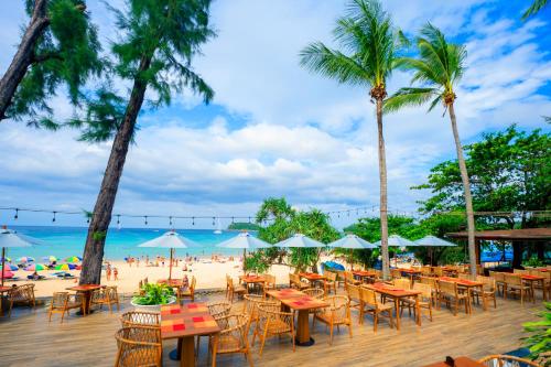 a beach with tables and chairs and palm trees at Beyond Kata in Kata Beach