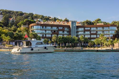 a boat in the water in front of a building at Princes' Palace Resort, Buyukada - Member of The Leading Hotels of the World in Adalar