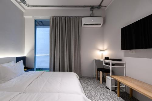 a hotel room with a bed and a desk and a window at Mowa Bangkok in Bangkok