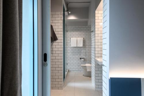 a bathroom with a toilet and a glass door at Mowa Bangkok in Bangkok