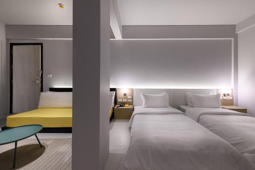 a bedroom with two beds and a yellow bed at Mowa Bangkok in Bangkok