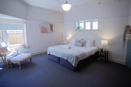 a white bedroom with a large bed and a chair at Parkside Spacious Central Family Retreat in Alfredton