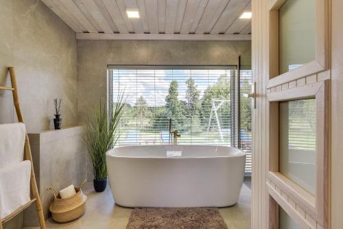 a bath tub in a bathroom with a large window at Meldai in Pabradė