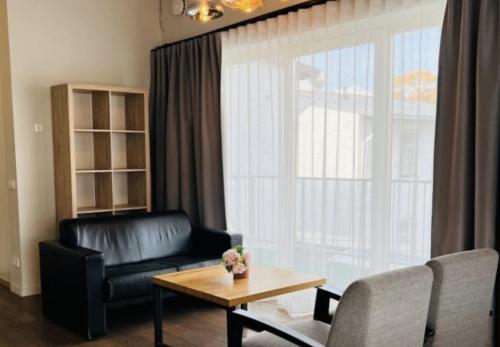 a living room with a black leather couch and a table at Arensburg Boutique Hotel & Spa in Kuressaare
