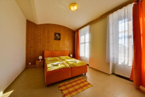 a bedroom with a bed and two large windows at Penzion Kameňák in Horní Planá