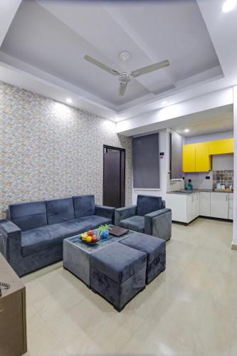 a living room with blue couches and a kitchen at Hotel The Rasa at Vasundhara in Ghaziabad