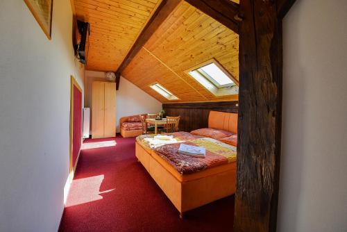 a attic room with a bed and a table at Penzion Kameňák in Horní Planá