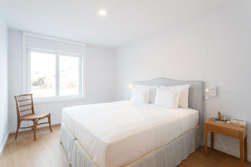 a bedroom with a white bed with a chair and a window at Cascais Center Luxury Triplex in Cascais