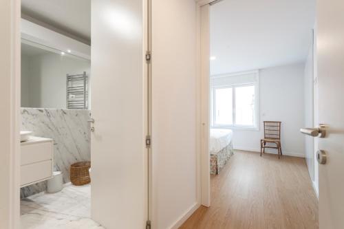 a white bedroom with a bed and a bathroom at Cascais Center Luxury Triplex in Cascais