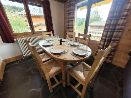 - une table en bois avec des chaises, des assiettes et des verres à vin dans l'établissement Chalet La SilÈne - Chalet de charme aux Chavannes avec vue et confort MAE-3411, aux Gets