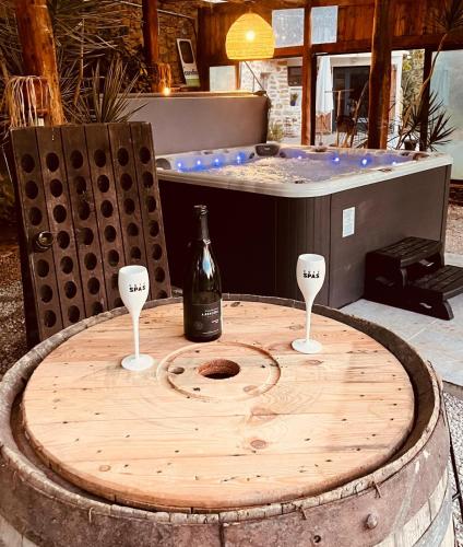 - une table en bois avec une bouteille de vin et 2 verres à vin dans l'établissement Maison à la campagne avec jacuzzi, à Grans