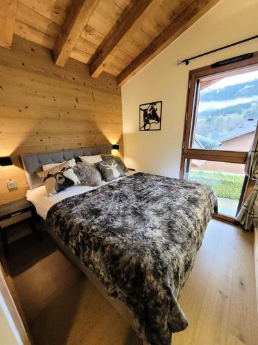 un grand lit dans une chambre avec une grande fenêtre dans l'établissement Résidence Le Genepi - APPARTEMENT NEUF - 2 CHAMBRES EN SUITE AVEC VUE MAE-3501, aux Gets
