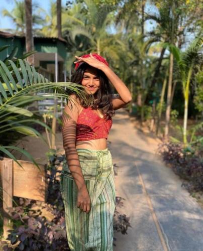 a woman wearing a hat standing on a road at Village Susegat Beach Resort in Morjim