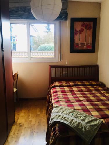 a bedroom with a bed with a plaid comforter and a window at Casa de Aurora in Rubí
