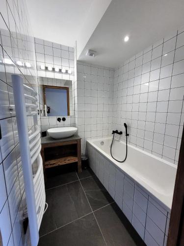 La salle de bains est pourvue de carrelage blanc, d'une baignoire et d'un lavabo. dans l'établissement Résidence PremiÈre Loge - appartement récent, belle piece de vie, jacuzzi avec vue MAE-3441, aux Gets