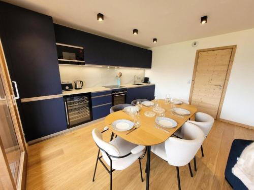 une salle à manger avec une table en bois et des chaises blanches dans l'établissement Résidence Le Genepi - APPARTEMENT NEUF 3 CHAMBRES - POELE A BOIS MAE-3351, aux Gets