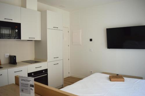 a kitchen with white cabinets and a bed in a room at Apartamentos Líbere Bilbao La Vieja in Bilbao