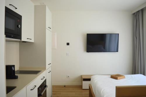 a white room with a bed and a tv at Apartamentos Líbere Bilbao La Vieja in Bilbao