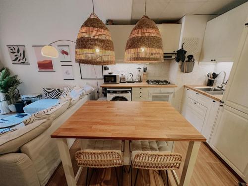 a kitchen with a wooden table and two hanging lights at Free housekeeping visits during your stay - StayShort - Cozy 1-Bedroom Apartment in Summer Residences JVC in Dubai