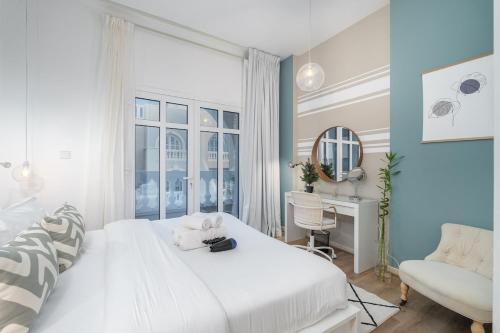 a white bedroom with a white bed and a desk at Free housekeeping visits during your stay - StayShort - Cozy 1-Bedroom Apartment in Summer Residences JVC in Dubai