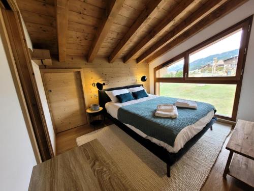 une chambre avec un lit et une grande fenêtre dans l'établissement Résidence Le Genepi - APPARTEMENT NEUF 3 CHAMBRES - POELE A BOIS MAE-3351, aux Gets