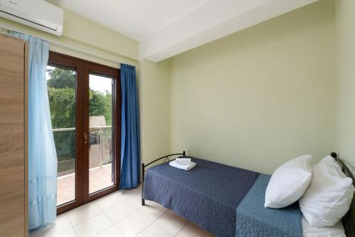 a bedroom with a bed and a large window at Villa Stratianna by PosarelliVillas in Módhion
