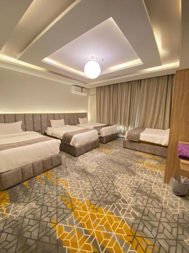 a hotel room with three beds and a carpet at Golden New Tulip Abha in Abha