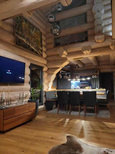 a living room with a television and a table and chairs at RALPH Cabin- Apuseni Mountains, Transylvania in Bucium