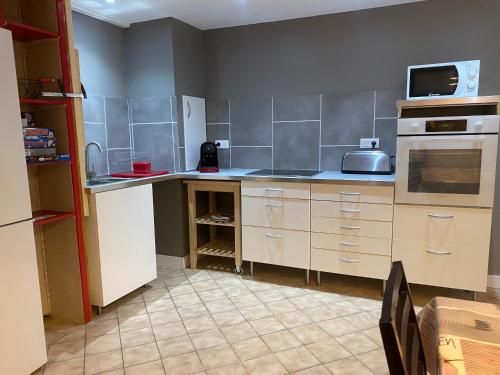 a kitchen with white cabinets and a stove top oven at Maison 3 chambres, 3 SdB, terrasse, piscine, spa in Meyrié