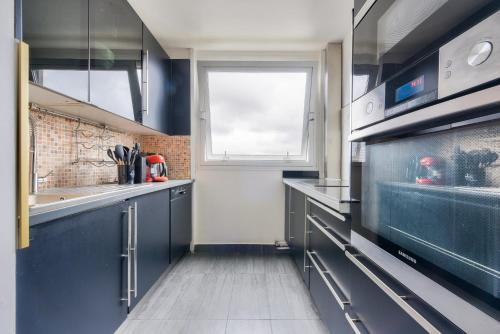 une cuisine avec des placards bleus et une fenêtre dans l'établissement Beautiful 1 bed flat at La Défense Near Metro 1, à Courbevoie