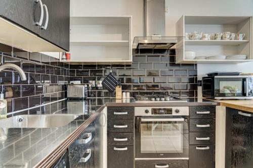a kitchen with stainless steel appliances and black tiles at Station Cottage in Long Hanborough