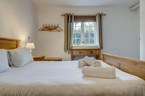 a bedroom with a large white bed with towels on it at Station Cottage in Long Hanborough