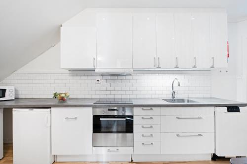 a white kitchen with white cabinets and a sink at Uppsala Lägenhetshotell in Uppsala