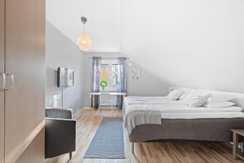 a white bedroom with a bed and a tv at Uppsala Lägenhetshotell in Uppsala